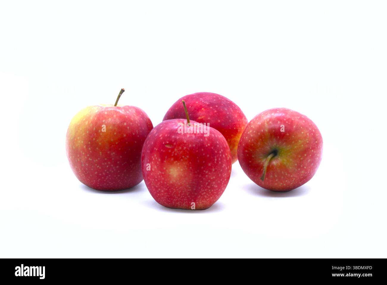 Gruppo di mele rosse fresche su un elegante banco per torte di vetro con due mele accanto, isolate su sfondo bianco. Ideale per concetti di cibo sano. Foto Stock