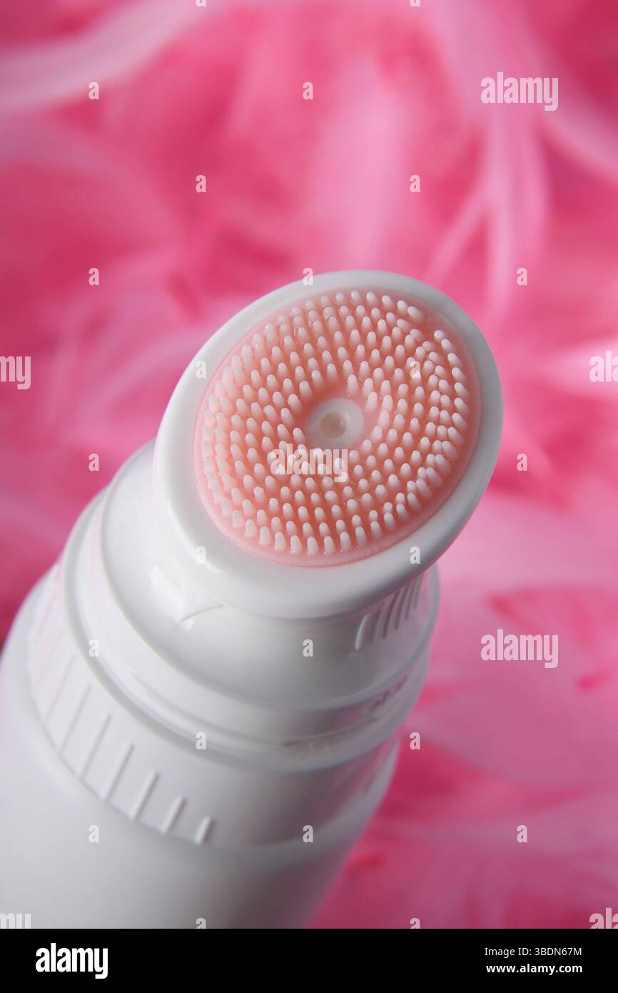 Primo piano di una spazzola bianca in plastica per il lavaggio su sfondo rosa con piume. Trucco. Pubblicità. Foto Stock