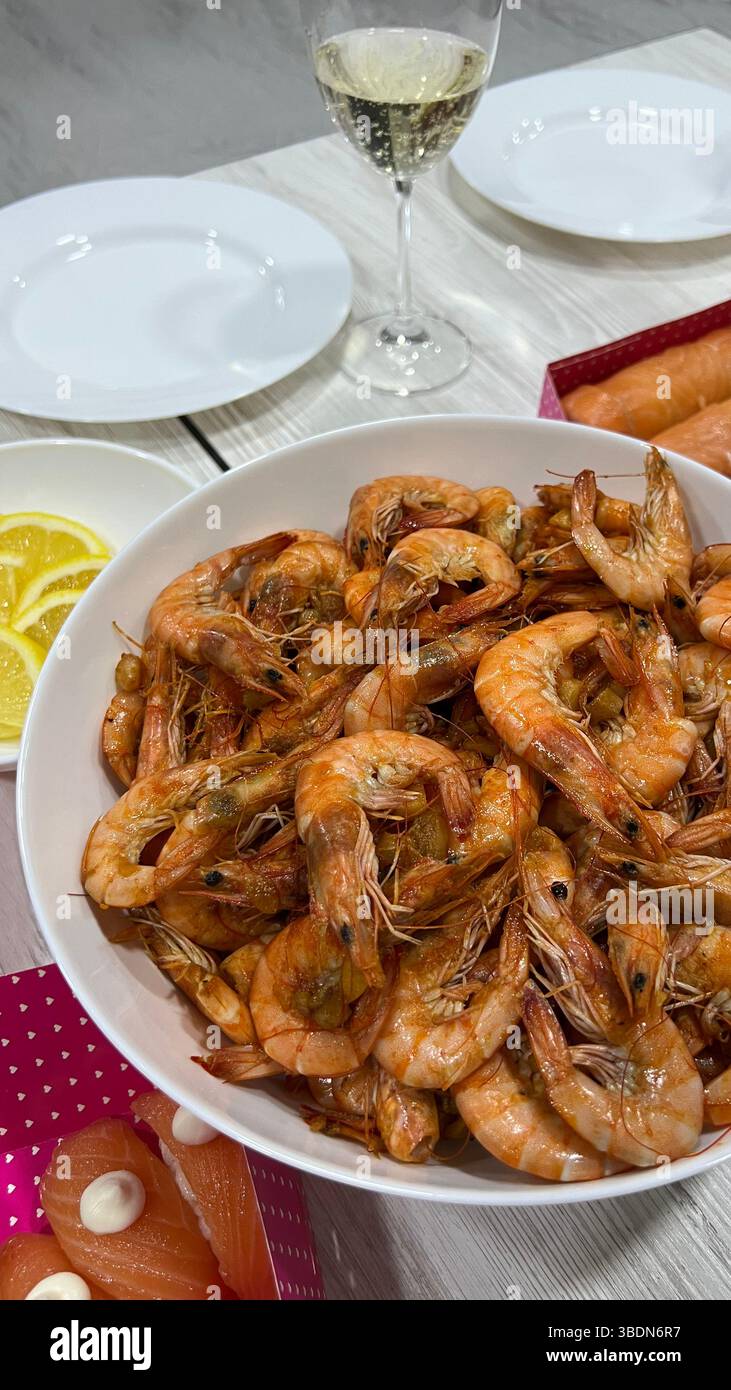 Un grande piatto bianco di gamberi fritti, un bicchiere di vino. Un incontro piacevole. Stile di vita. - Immagine stock catturata con smartphone
