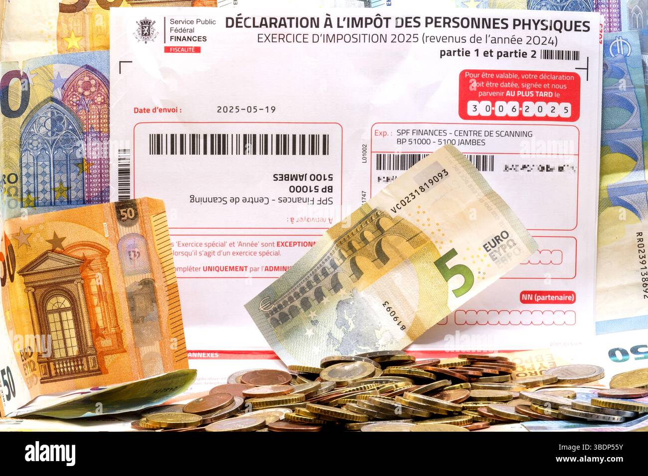Monete in euro da un borsello circondato da banconote in euro e foglio delle imposte sul reddito da compilare | Pièces d'euros hors d'un porte-monnaie entourés de billets d'e Foto Stock