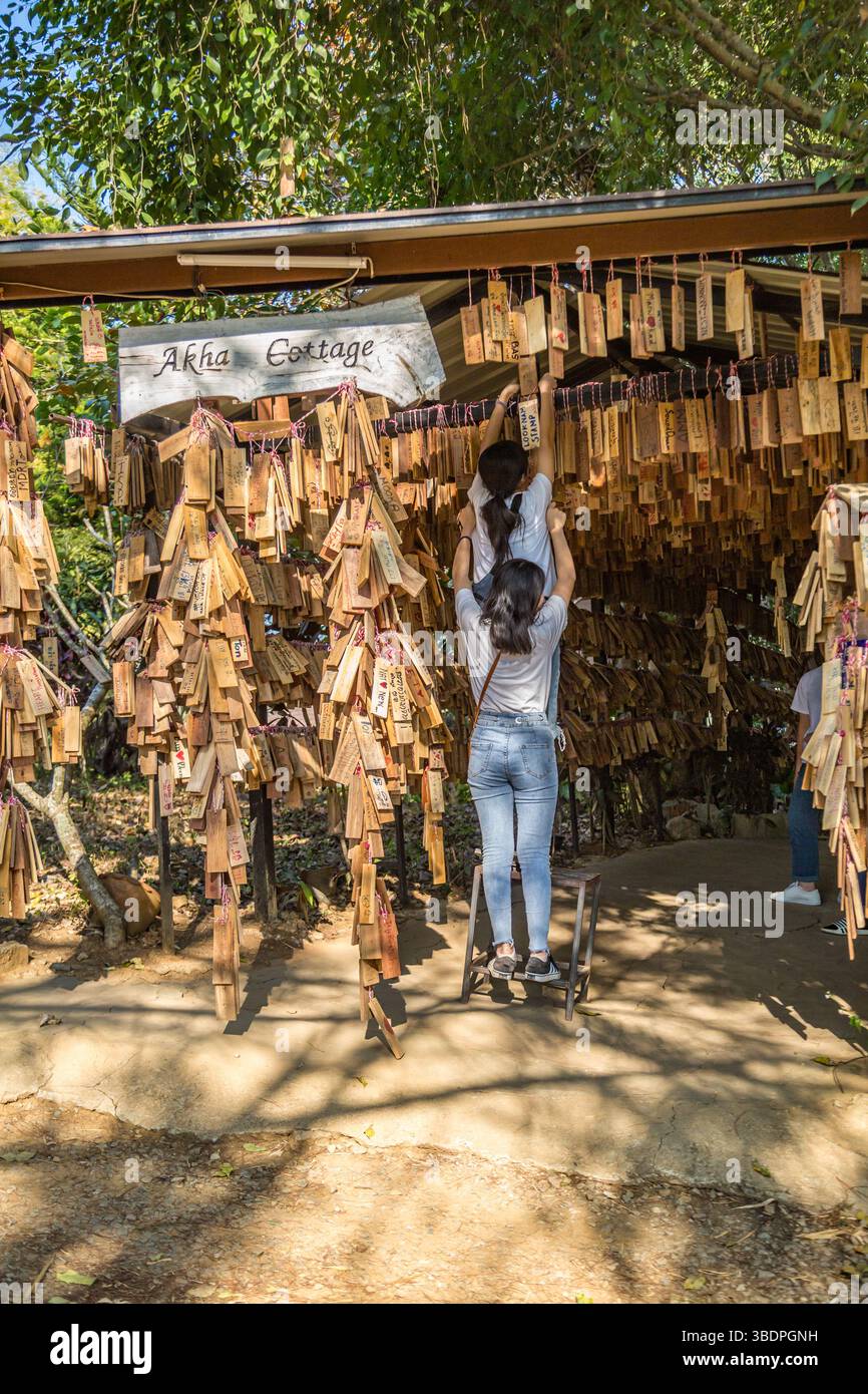 Le donne thailandesi appendono la loro targa di messaggio personale vicino all'ingresso del ristorante e caffetteria Akha Cottage a Chiang Rai, Thailandia Foto Stock