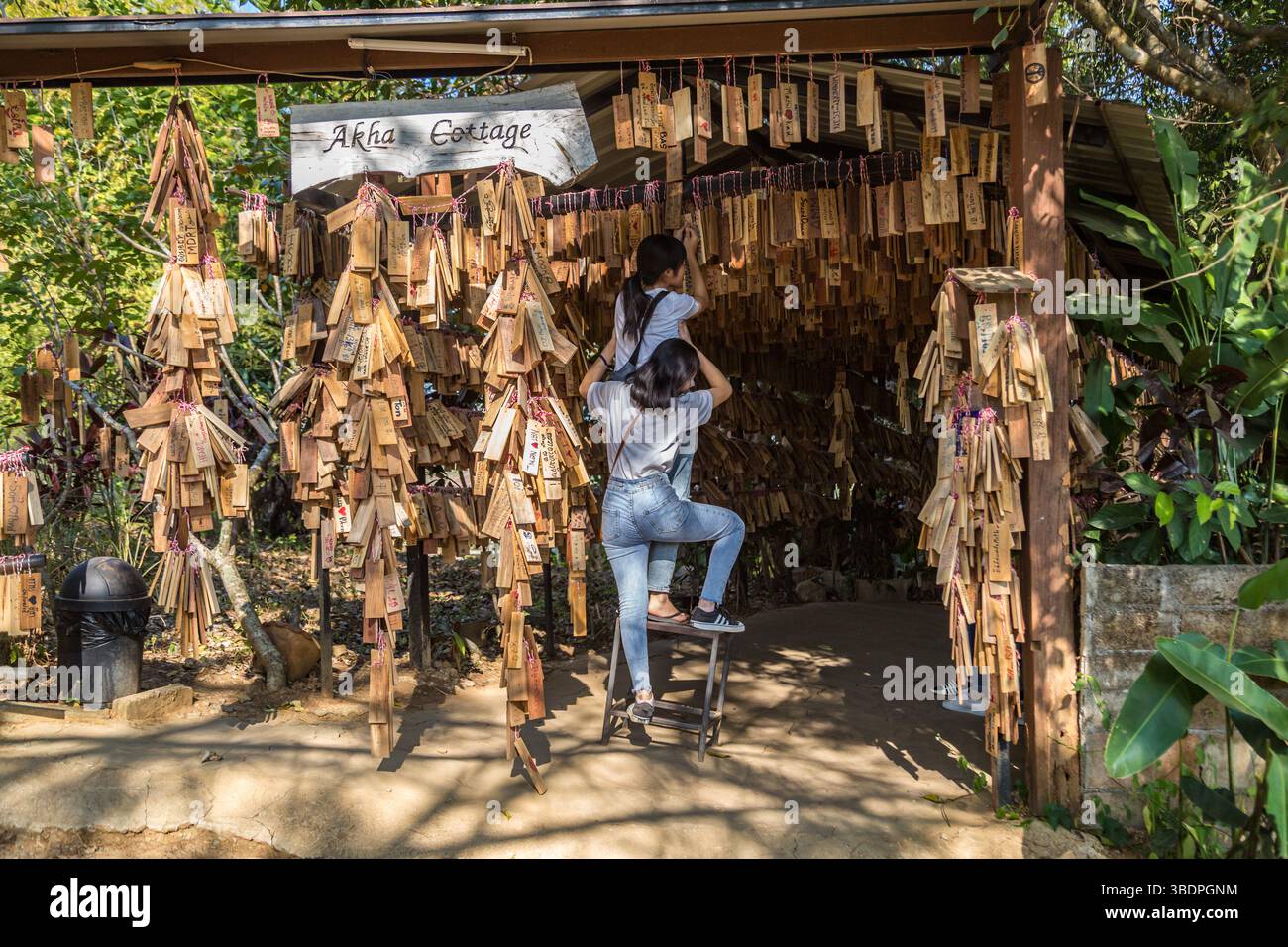 Le donne thailandesi appendono la loro targa di messaggio personale vicino all'ingresso del ristorante e caffetteria Akha Cottage a Chiang Rai, Thailandia Foto Stock