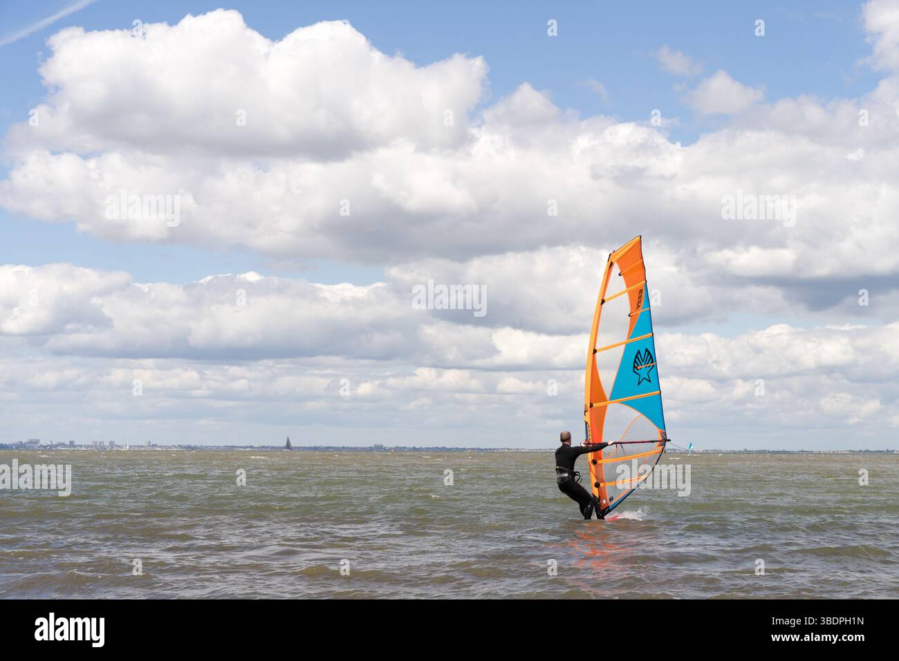 Swale Sittingbourne, Regno Unito. 25 maggio 2025. Tempo nel Regno Unito: Domenica soleggiata lungo la costa del Kent: Con una leggera brezza in aria, i windsurf si tuffano in acqua su tavole a vela mentre gli amanti della spiaggia si crogiolano nel calore del sole pomeridiano. Un vivace mix di relax e avventura mentre la scena costiera prende vita Credit: xiu bao/Alamy Live News Foto Stock