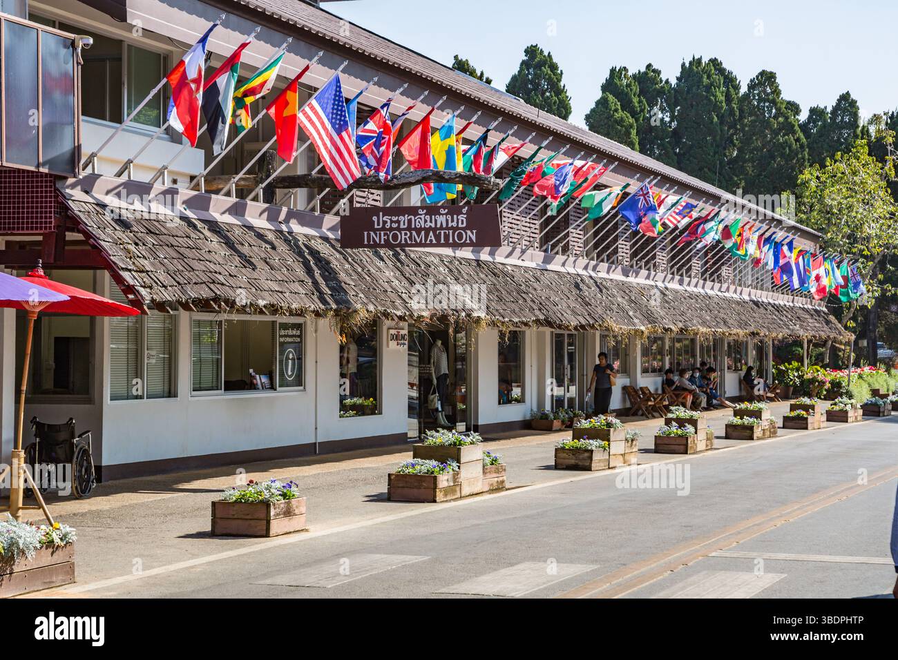 L'edificio con molte bandiere nazionali contiene il centro informazioni, i negozi al dettaglio e il ristorante all'interno dell'attrazione turistica Doi Tung a Chiang Rai, T. Foto Stock L'edificio con molte bandiere nazionali contiene il centro informazioni, i negozi al dettaglio e il ristorante all'interno dell'attrazione turistica Doi Tung a Chiang Rai, T. Foto Stock