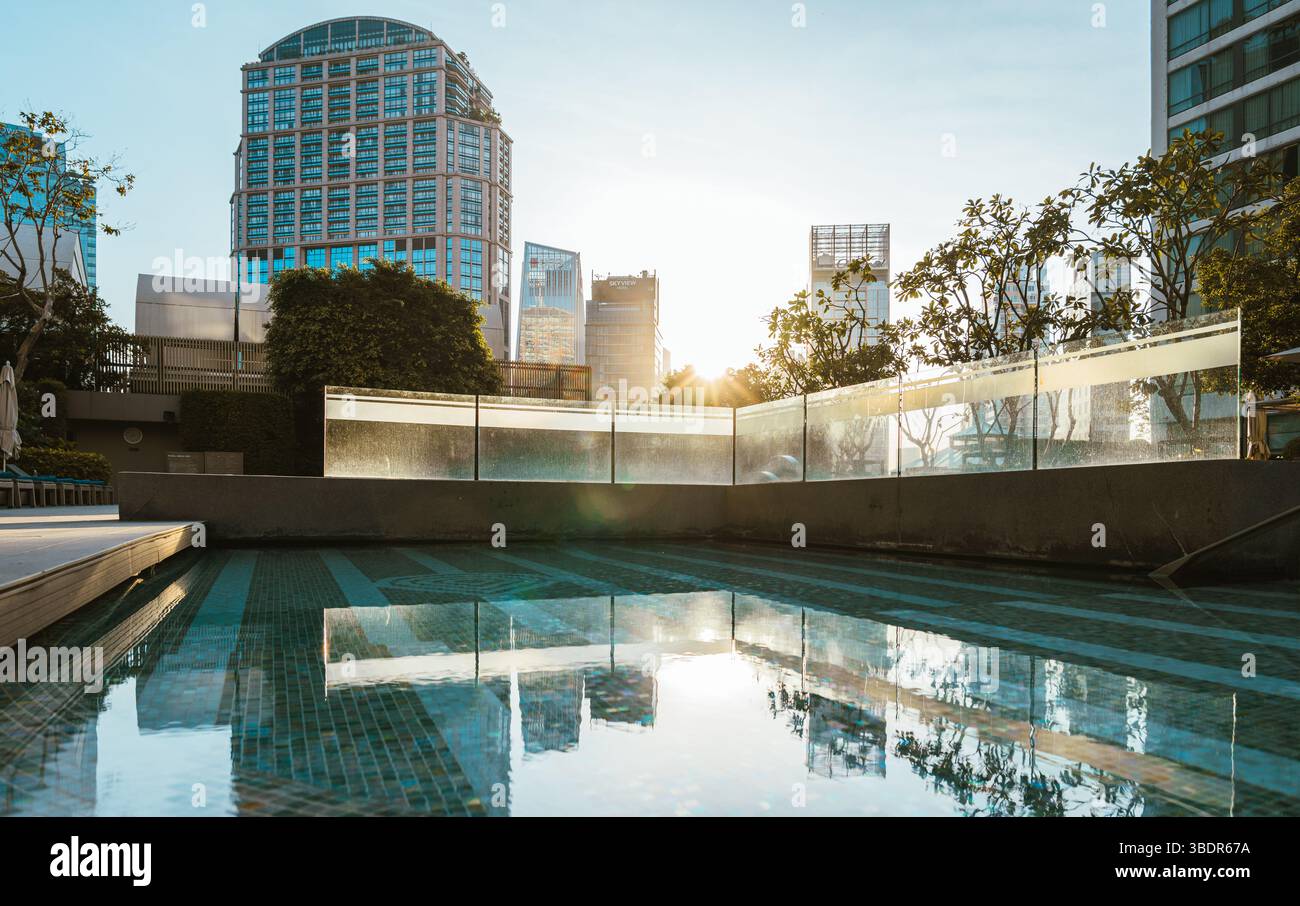 Il bagliore mattutino illumina una piscina sul tetto con vista dello skyline di Bangkok Foto Stock