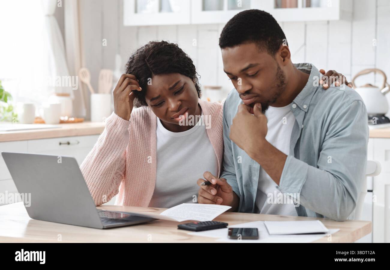 Sottolineato Coppia Nera calcolo bilancio famiglia in cucina, sofferenza crisi finanziaria Foto Stock