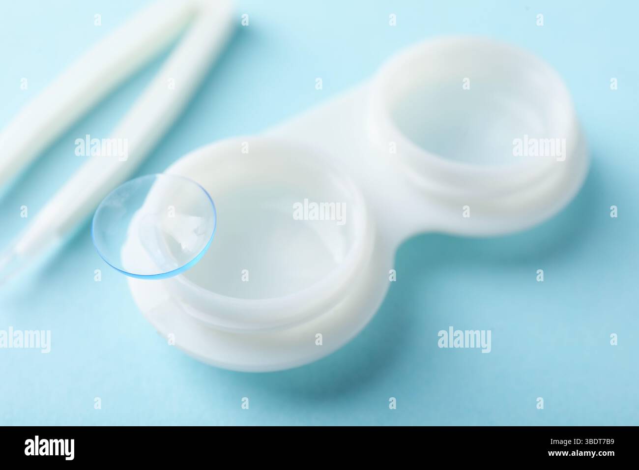 Lenti a contatto, custodia e pinzette su sfondo azzurro, primo piano Foto Stock