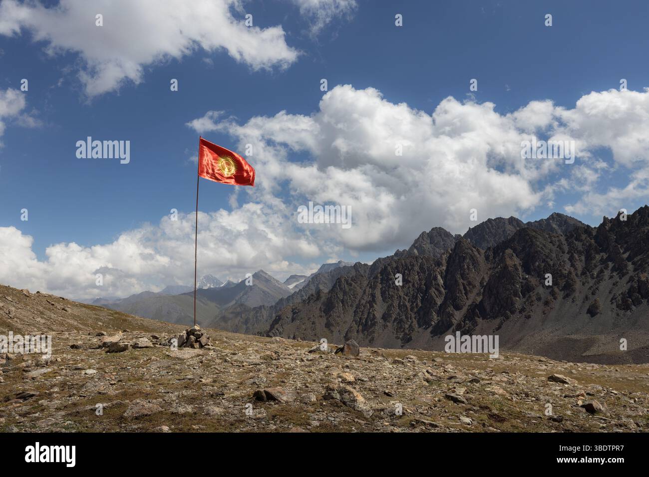 Bandiera nazionale del Kirghizistan posta sulla cima della montagna nella valle panoramica della catena montuosa di Tien Shan Foto Stock