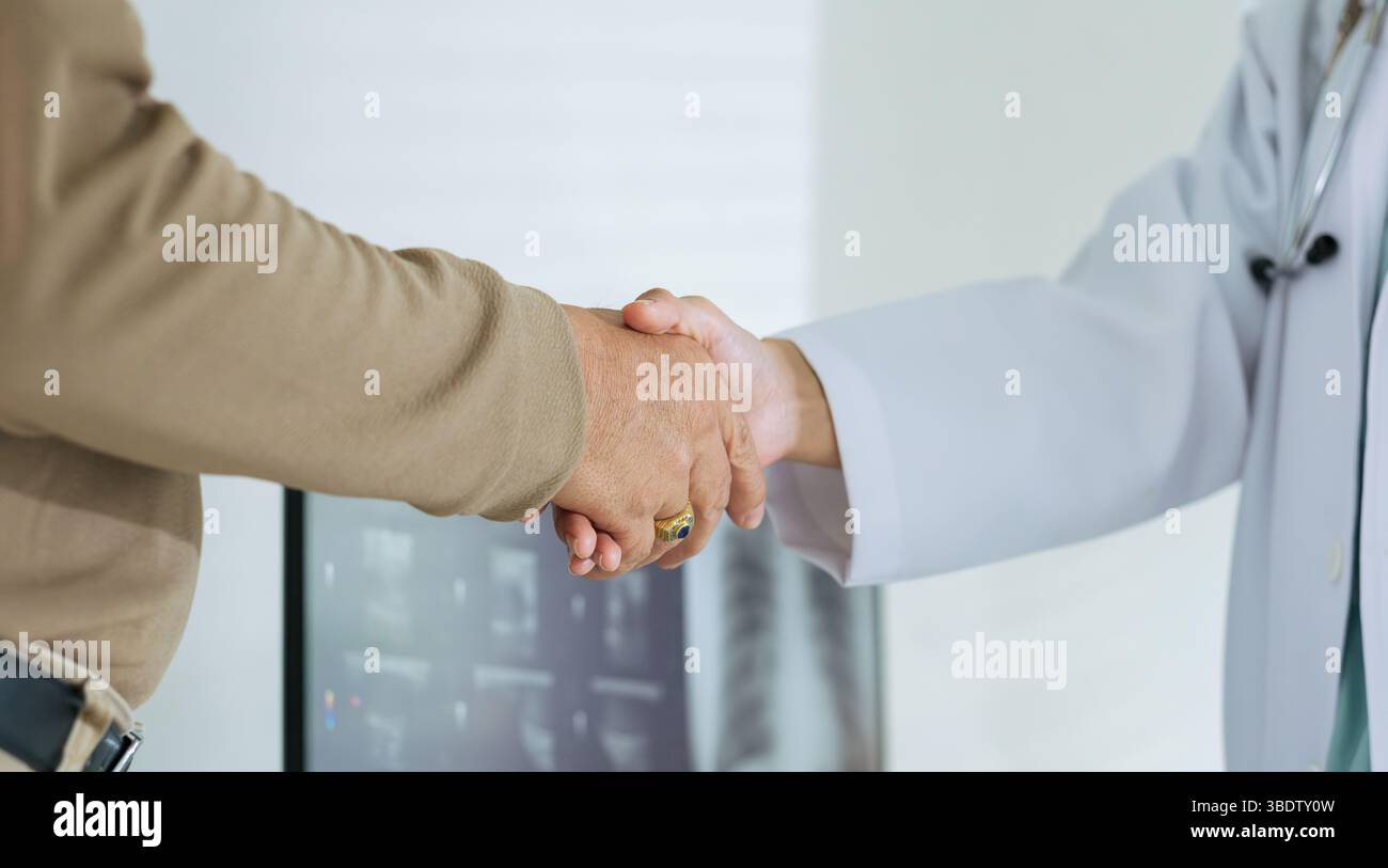 primo piano di un medico e di un paziente anziano che stringono la mano durante una visita in ospedale. Foto Stock