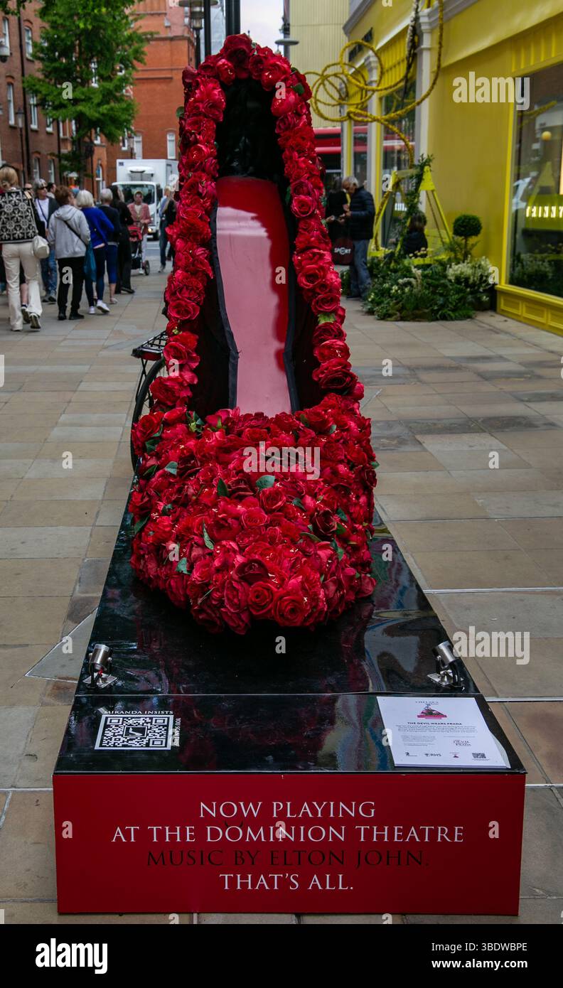 Una grande scultura di scarpa adornata con rose rosse esposta a Sloane St per Chelsea in fiore che pubblicizza il Diavolo indossa Prada al Dominion Theatre. Foto Stock