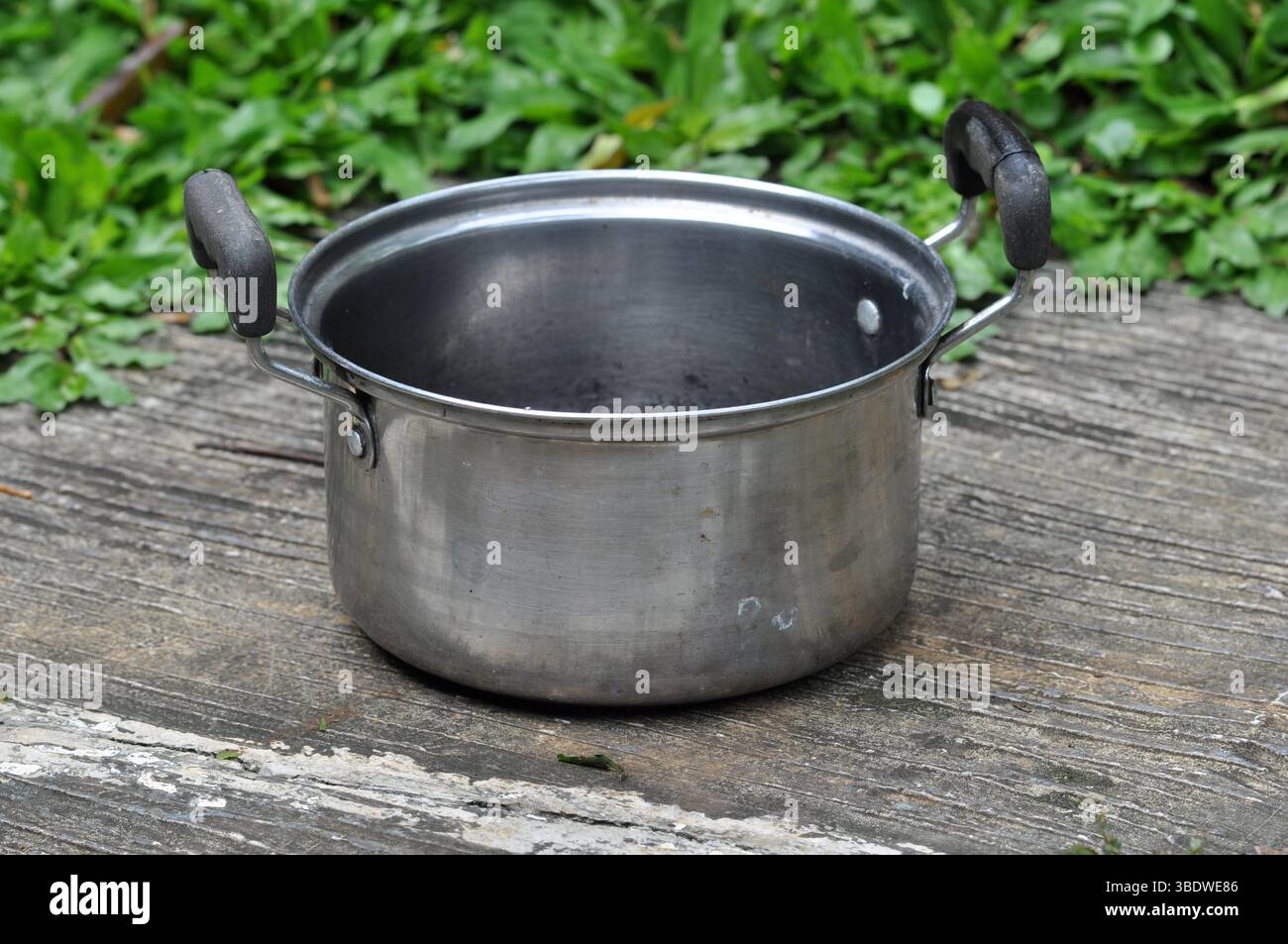 Pentola di cottura in acciaio inox su superficie in legno rustico Foto Stock