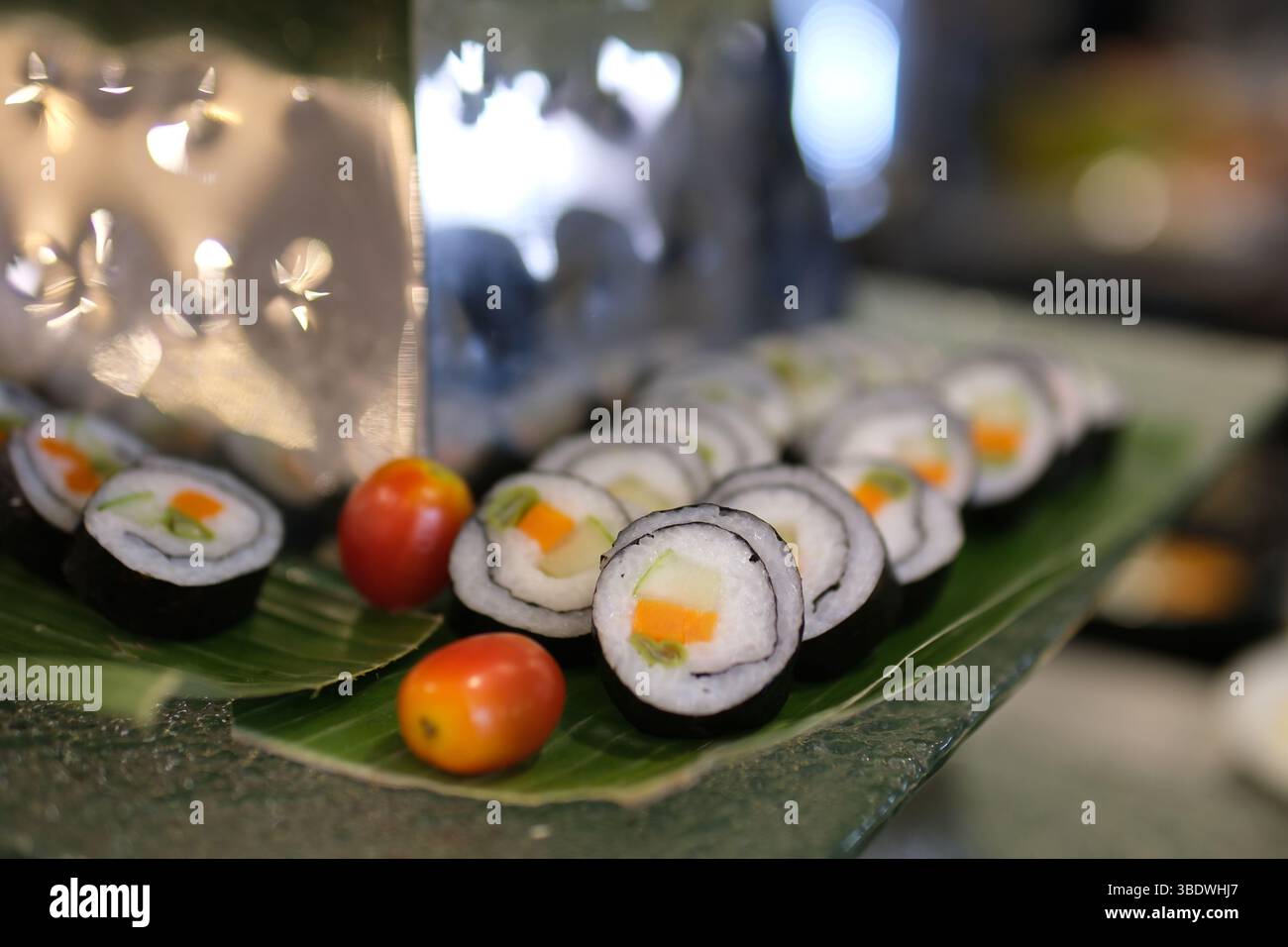 Sushi coreano, kimbap, con prosciutto, verdure e lattuga. Processo di cottura, preparazione del kimbap fatto in casa, cottura passo dopo passo e taglio a fette con le mani nella foto, vista dall'alto Foto Stock