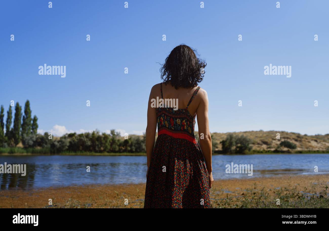 Donna contemplativa che guarda lo stagno Foto Stock