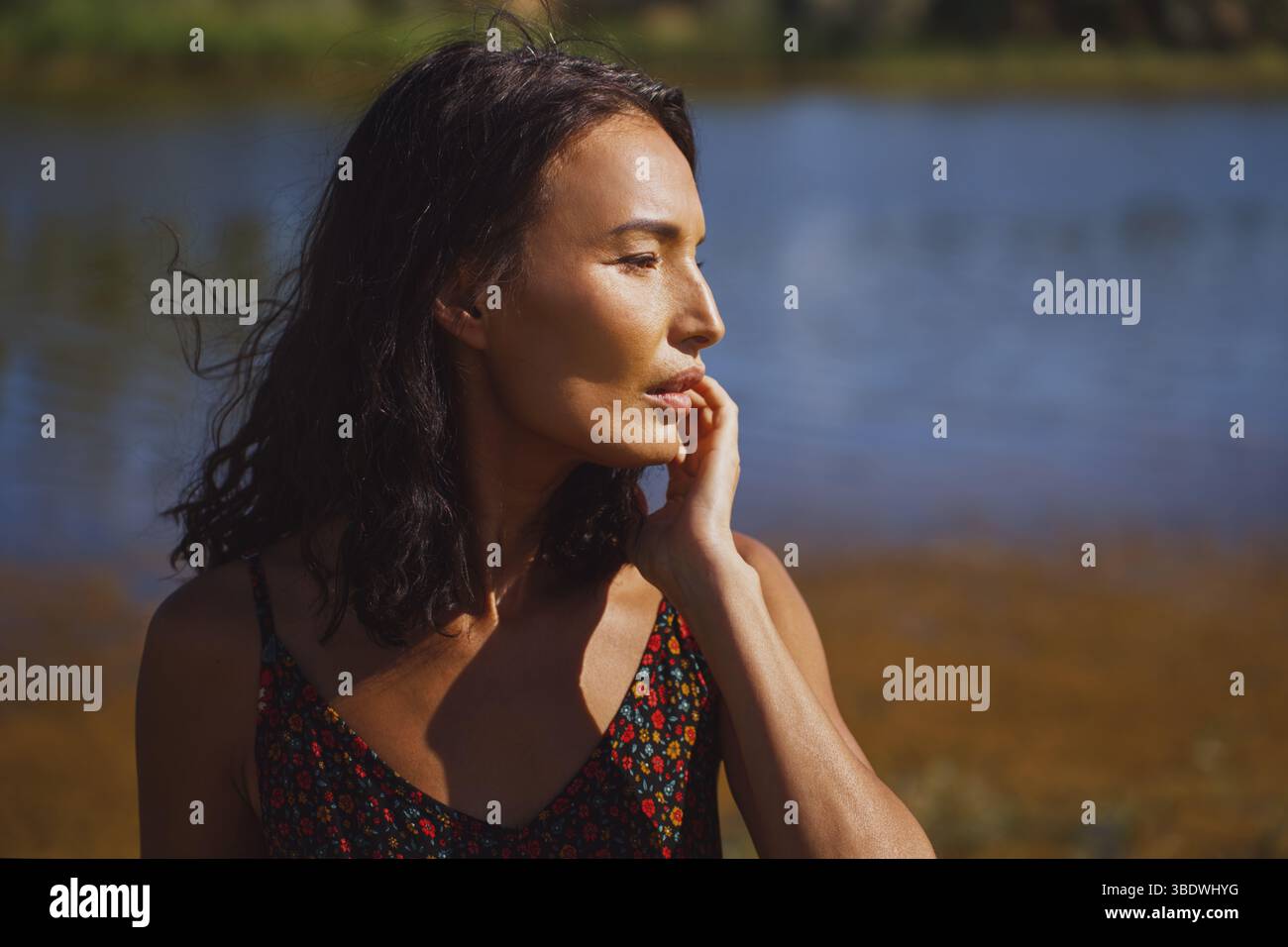 Donna contemplativa di fronte allo stagno Foto Stock