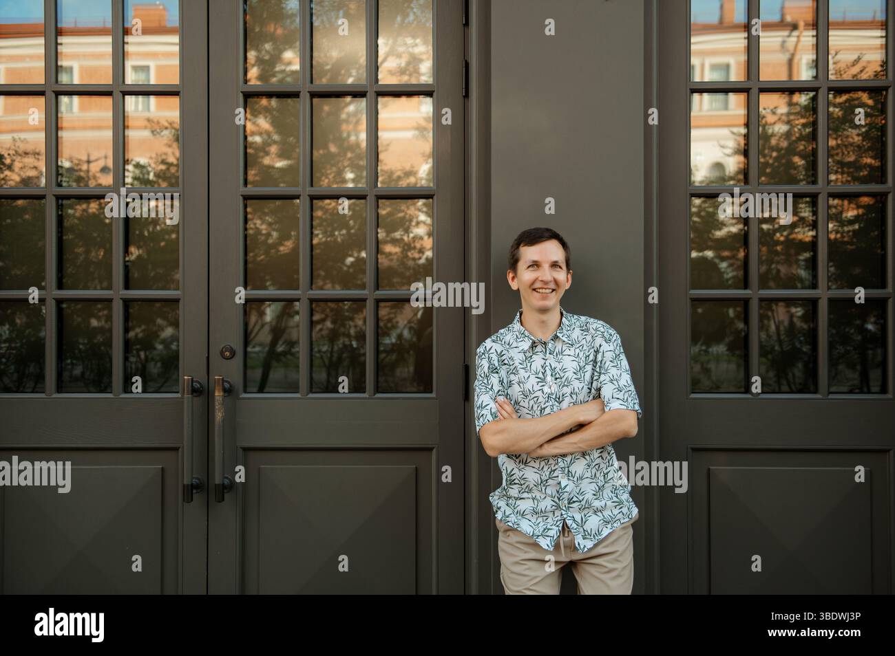 Un uomo che si trova in un edificio moderno con porte di vetro Foto Stock