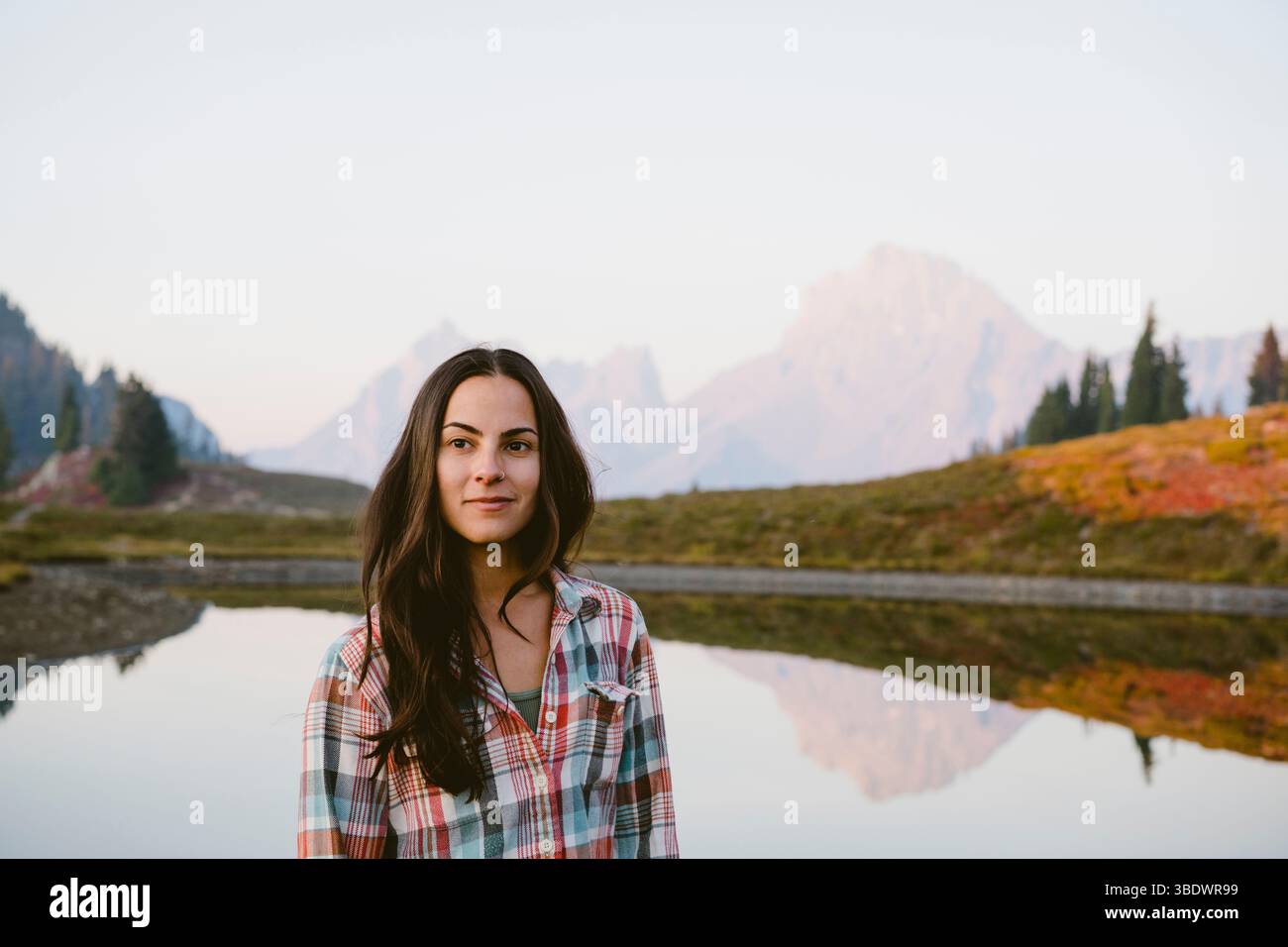 Giovane donna di fronte al lago alpino con riflessi Foto Stock