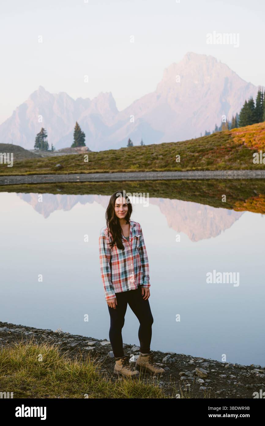 Giovane donna di fronte al lago alpino con riflessi Foto Stock