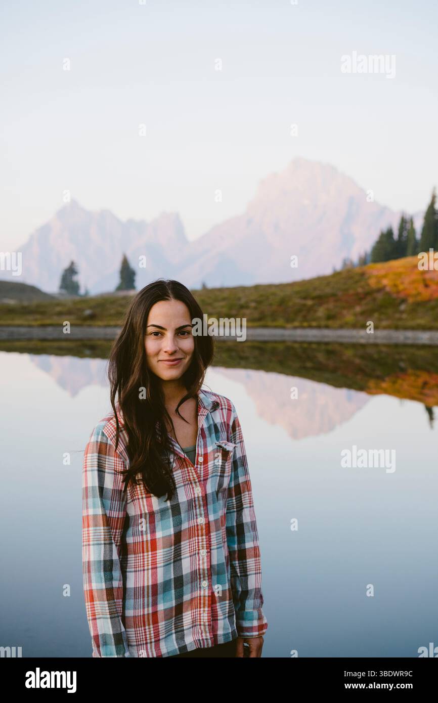 Giovane donna di fronte al lago alpino con riflessi Foto Stock