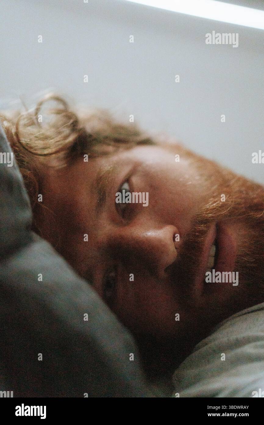 Ritratto di un uomo che si rilassa sul letto a casa, da vicino Foto Stock