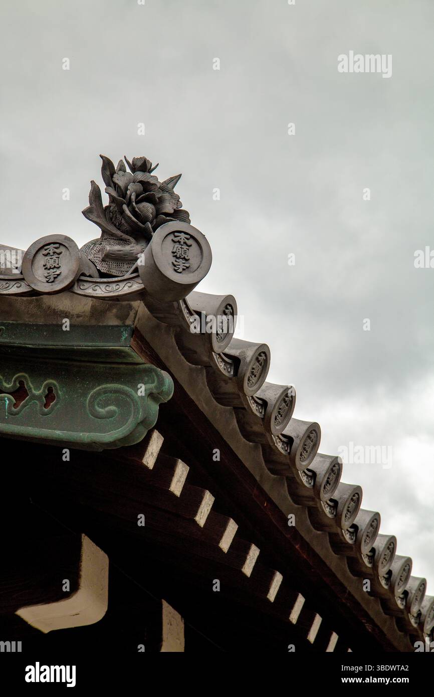 Primo piano di un ornamento di fiori di pietra sul tetto di un tempio di Kyoto, adagiato contro un cielo nuvoloso in Giappone Foto Stock