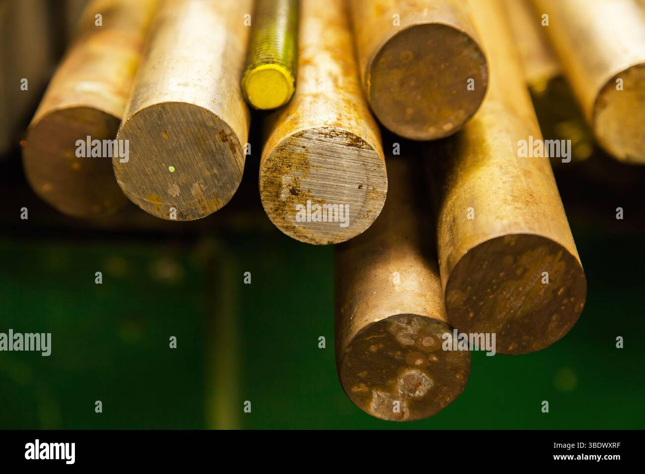 Grandi barre tonde in bronzo e barre filettate in acciaio si trovano su un ripiano, in primo piano. Foto Stock