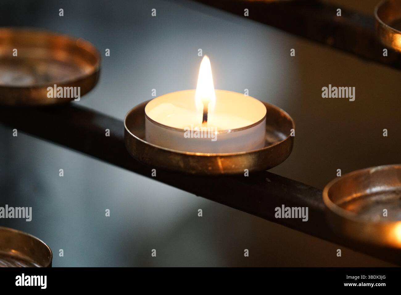 Primo piano di una Tealight bruciante su un portacandele in metallo. Chichester, Regno Unito Foto Stock