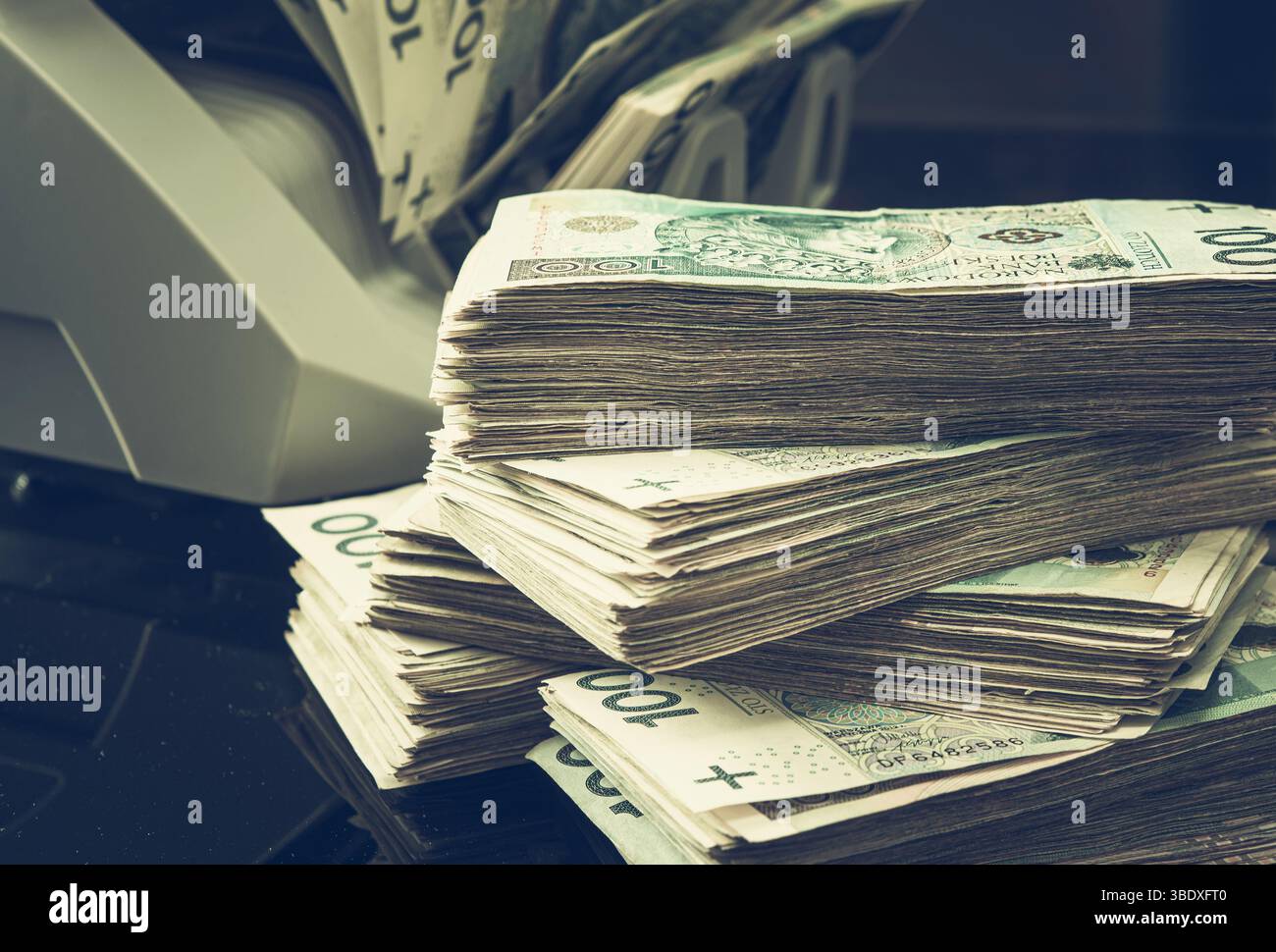 Le banconote in zloty polacche in bundle sono ordinatamente impilate accanto a una macchina per il conteggio del denaro in un ambiente commerciale. Foto Stock