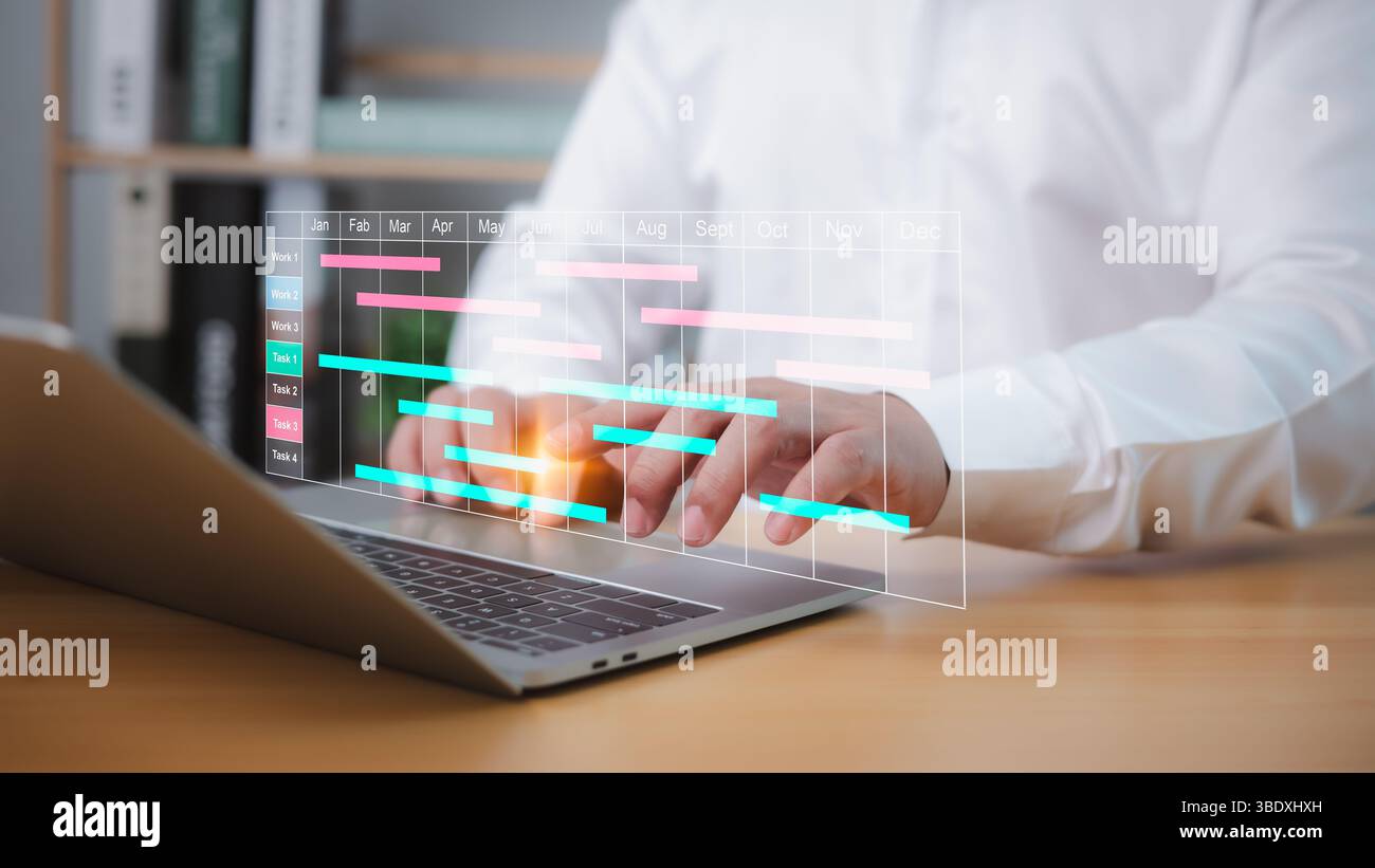 Uomo d'affari che utilizza un software di gestione dei progetti su un laptop per pianificare le attività, aggiornare i grafici di Gantt e gestire il flusso di lavoro, migliorando la pianificazione e la produttività Foto Stock