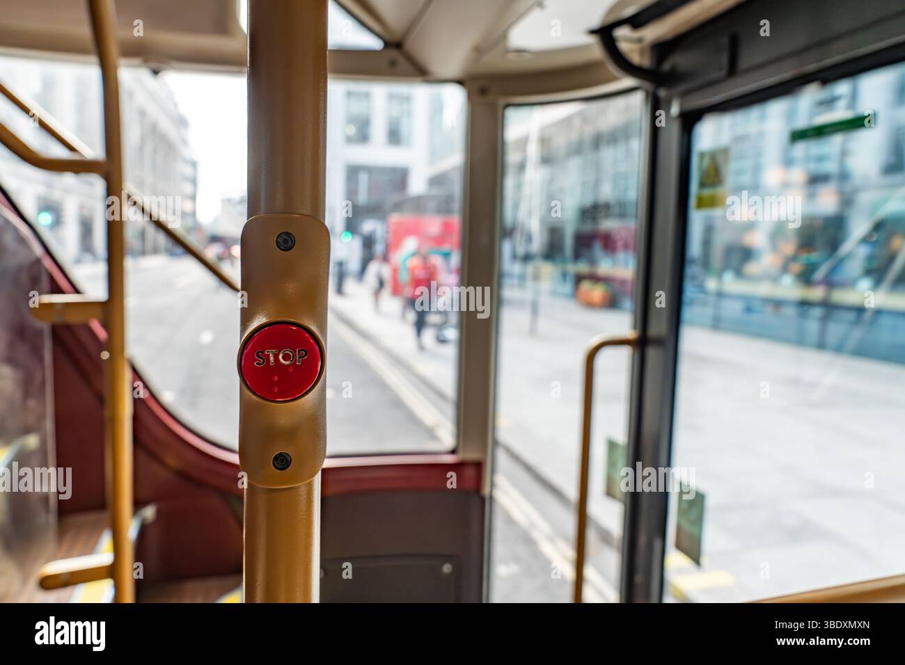 Primo piano del pulsante della fermata rossa su un autobus di Londra con la City Street visibile attraverso la finestra, catturando l'esperienza quotidiana dei Commuter. Foto Stock