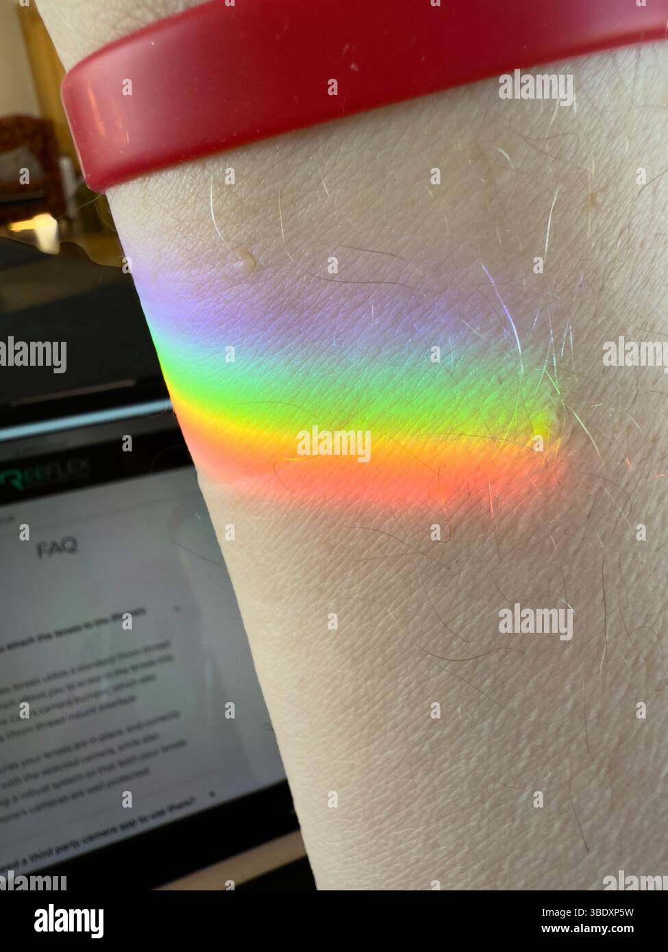 Uno spettro casuale di colori sul braccio di una persona creato dai raggi del sole attraverso un pezzo di vetro tagliato Foto Stock