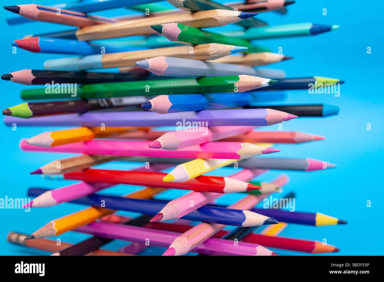 Pastelli colorati impilati impilati a forma di torre per primo piano su blu Foto Stock