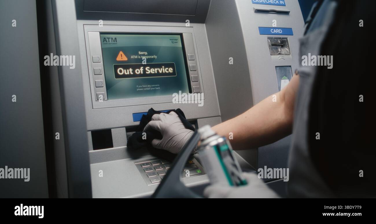 Pulizia pulizia dello schermo bancomat vandalizzato con Rag, rimozione di graffiti, etichette scarabocchiate da distributore automatico, bancomat. Servizio di pulizia, danni alla proprietà, atti vandalici delle apparecchiature bancarie pubbliche. Foto Stock