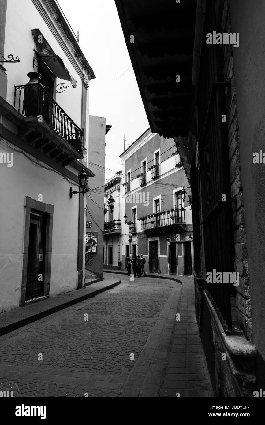 Guanajuato City, Messico - 30 maggio 2016: Un gruppo di persone sta in piedi su una strada acciottolata, parlando, di fronte ad un edificio con balconi. Foto Stock