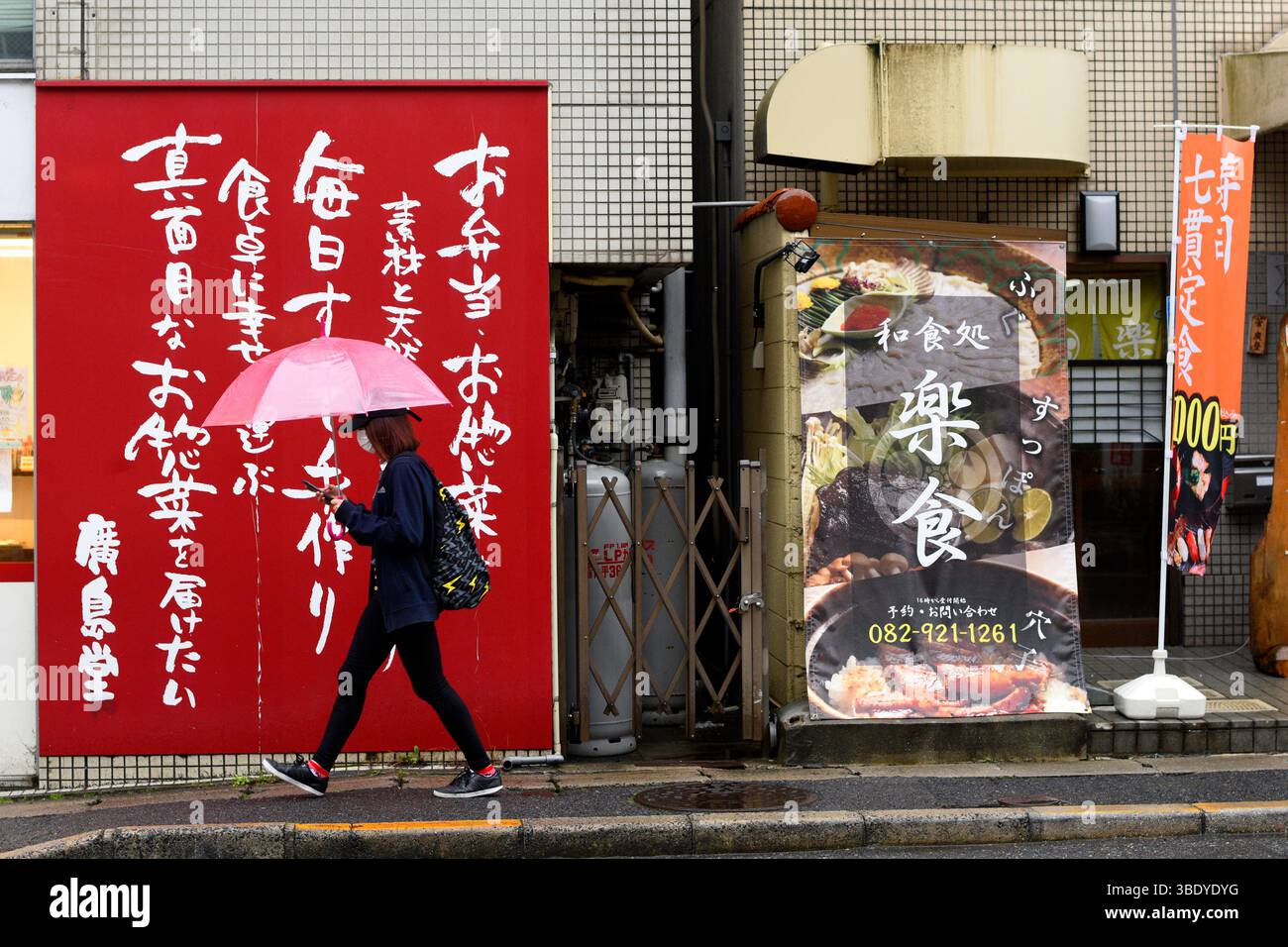 Persone con ombrello che camminano sulla strada di Hiroshima, Giappone, Asia. Foto Stock