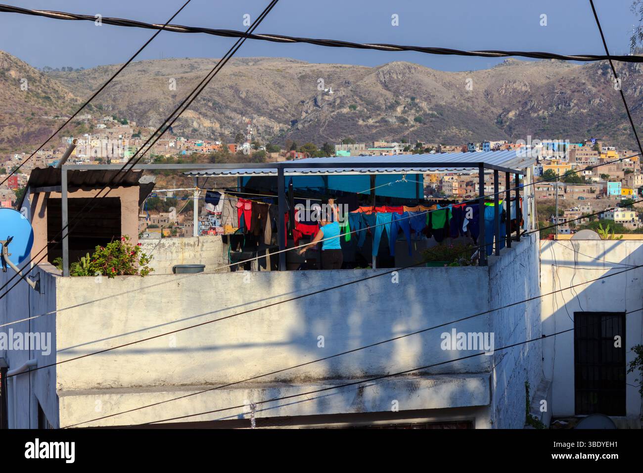 Guanajuato City, Messico - 30 maggio 2016: Una donna appende il bucato su una linea di abbigliamento sul tetto, approfittando del sole per asciugare i suoi vestiti. Foto Stock