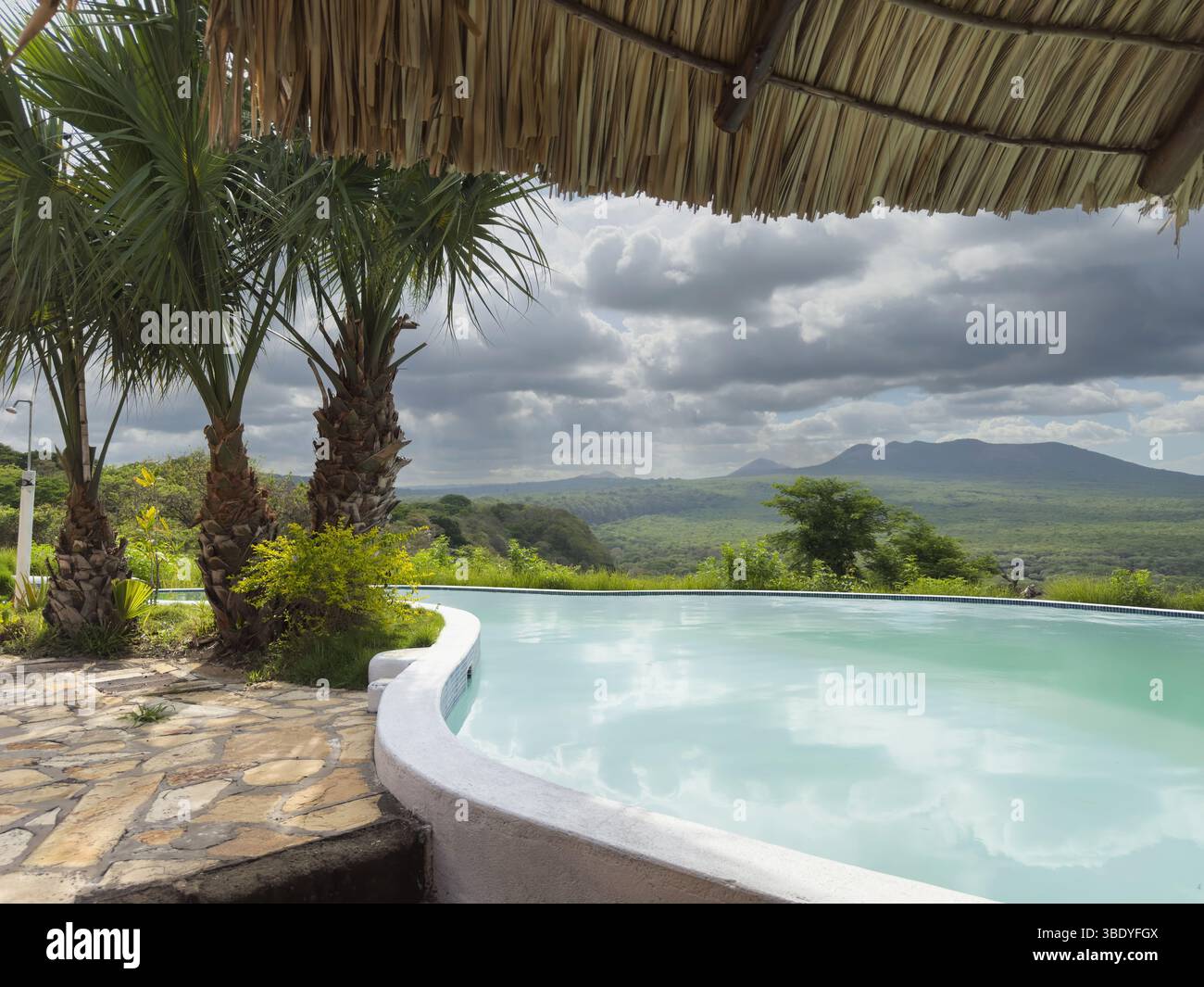 La piscina Infinity offre una splendida vista delle montagne lontane e della vegetazione lussureggiante nelle giornate nuvolose. Foto Stock