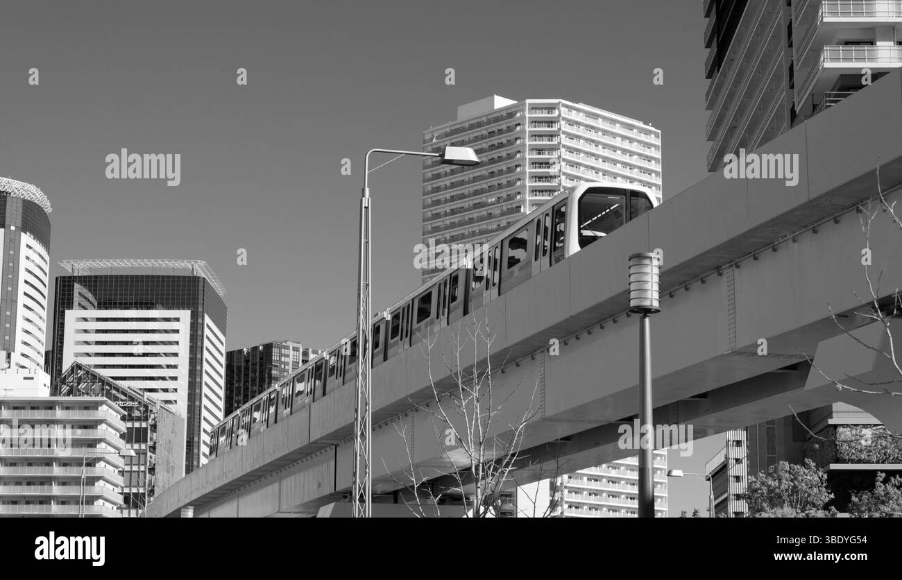 Il treno della linea Yurikamome attraversa lo skyline di Tokyo in questa cornice monocromatica Foto Stock