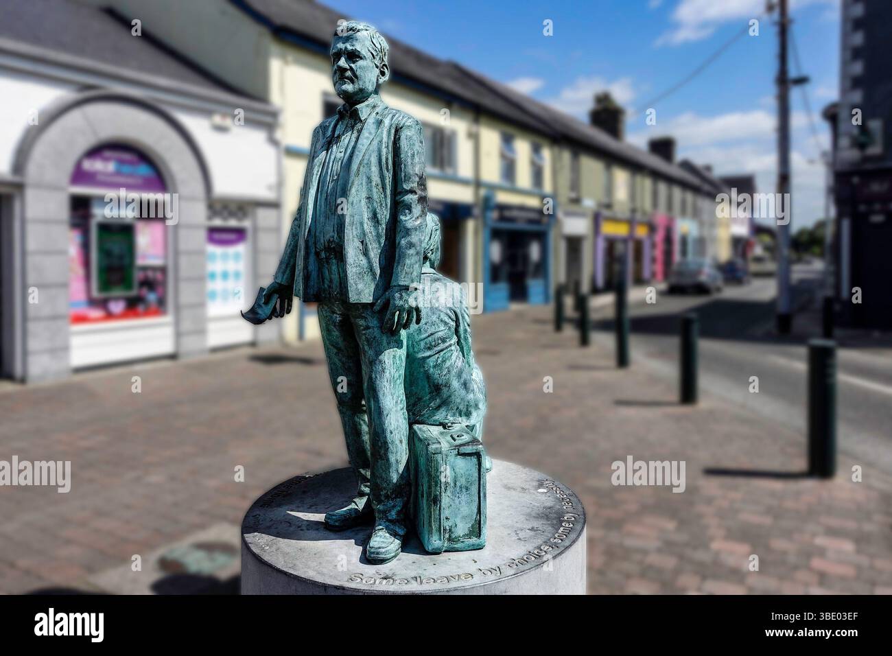La scultura "The Journey" a Longford, Irlanda, onora l'emigrazione, mostrando un uomo con valigia e figura seduta, simboleggiando la partenza e la memoria. Foto Stock