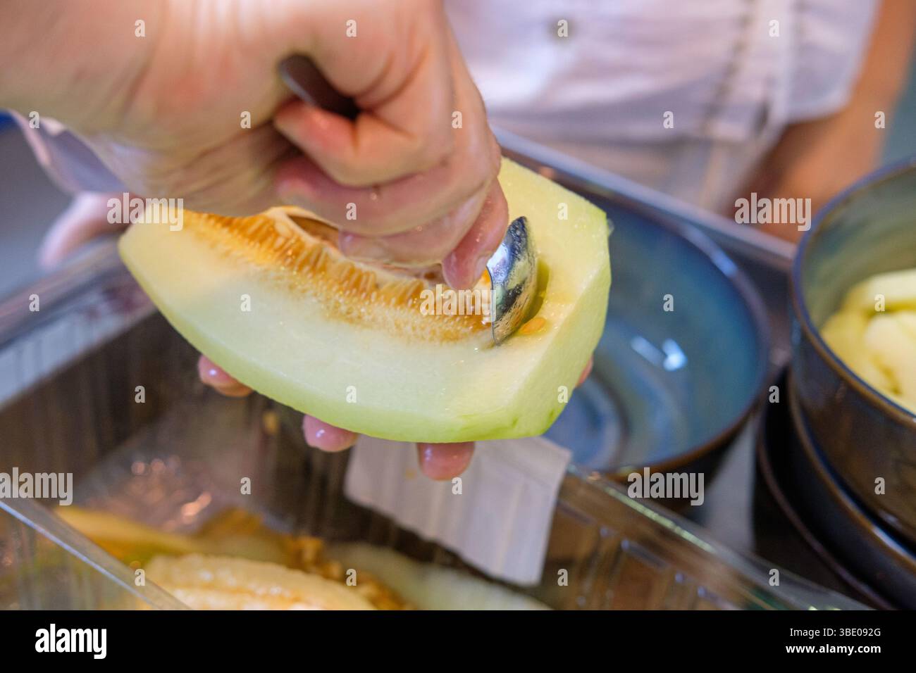 preparazione del melone di melone fresco: rimozione dei semi con un cucchiaio in cucina Foto Stock