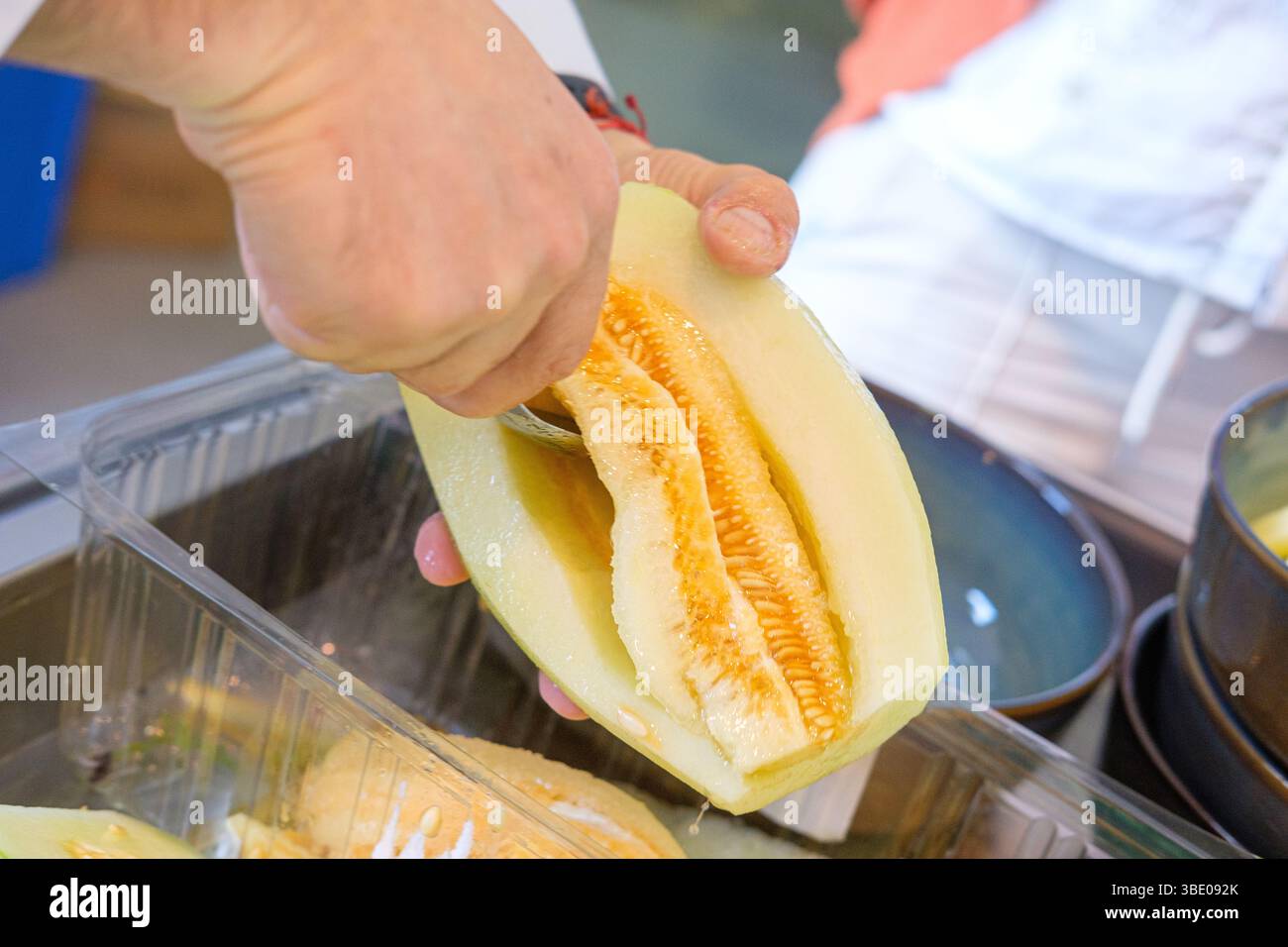 preparazione fresca al melone per una sana alimentazione, desemina delle mani con cucchiaio Foto Stock