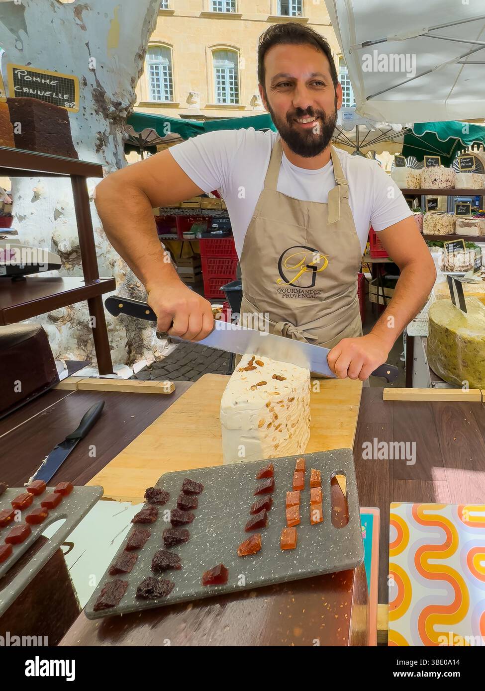 AIX-en-Provence, Francia - 10 luglio 2024: Negozio di torrone al mercato pubblico in Place Richelme. Grandi pezzi di gusti diversi, di cui il venditore taglia fuori Foto Stock