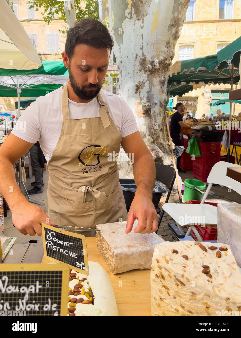 AIX-en-Provence, Francia - 10 luglio 2024: Negozio di torrone al mercato pubblico in Place Richelme. Grandi pezzi di gusti diversi, di cui il venditore taglia fuori Foto Stock