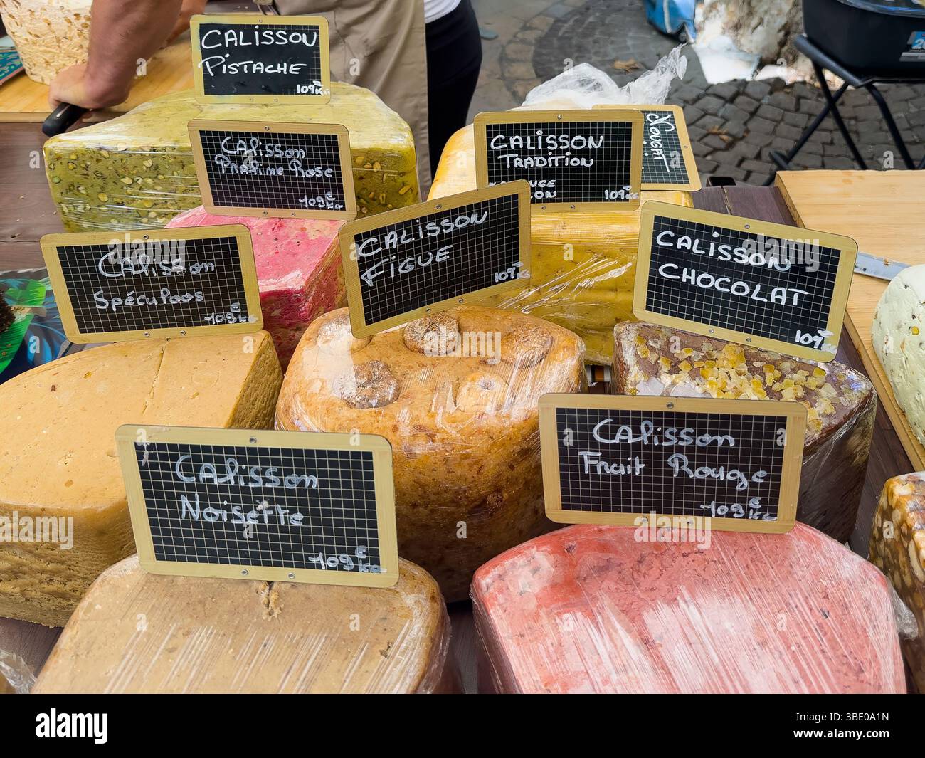 AIX-en-Provence, Francia - 10 luglio 2024: Negozio Calisson al mercato pubblico in Place Richelme. Grandi pezzi di gusti diversi in mostra Foto Stock