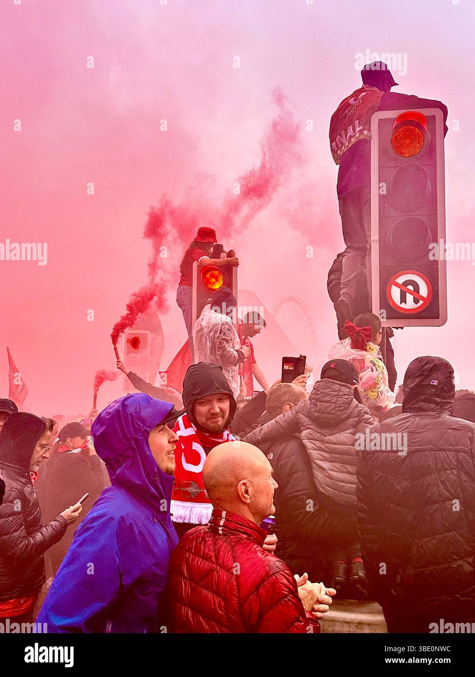 I tifosi del Liverpool ondeggiano rossi, si abbracciano e scalano i semafori durante la parata della vittoria di calcio su Strand Street, Liverpool, Regno Unito. 26 maggio 2025. - Immagine stock catturata con smartphone