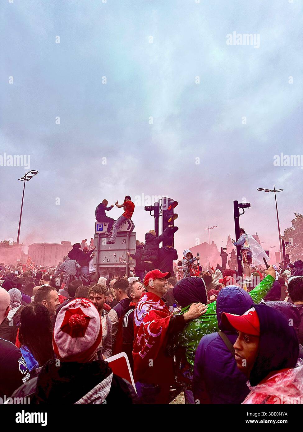 I tifosi del Liverpool si abbracciano e festeggiano sullo Strand mentre il fumo rosso riempie l'aria durante la parata della vittoria del calcio. Liverpool, Regno Unito, 26 maggio 2025. Foto Stock