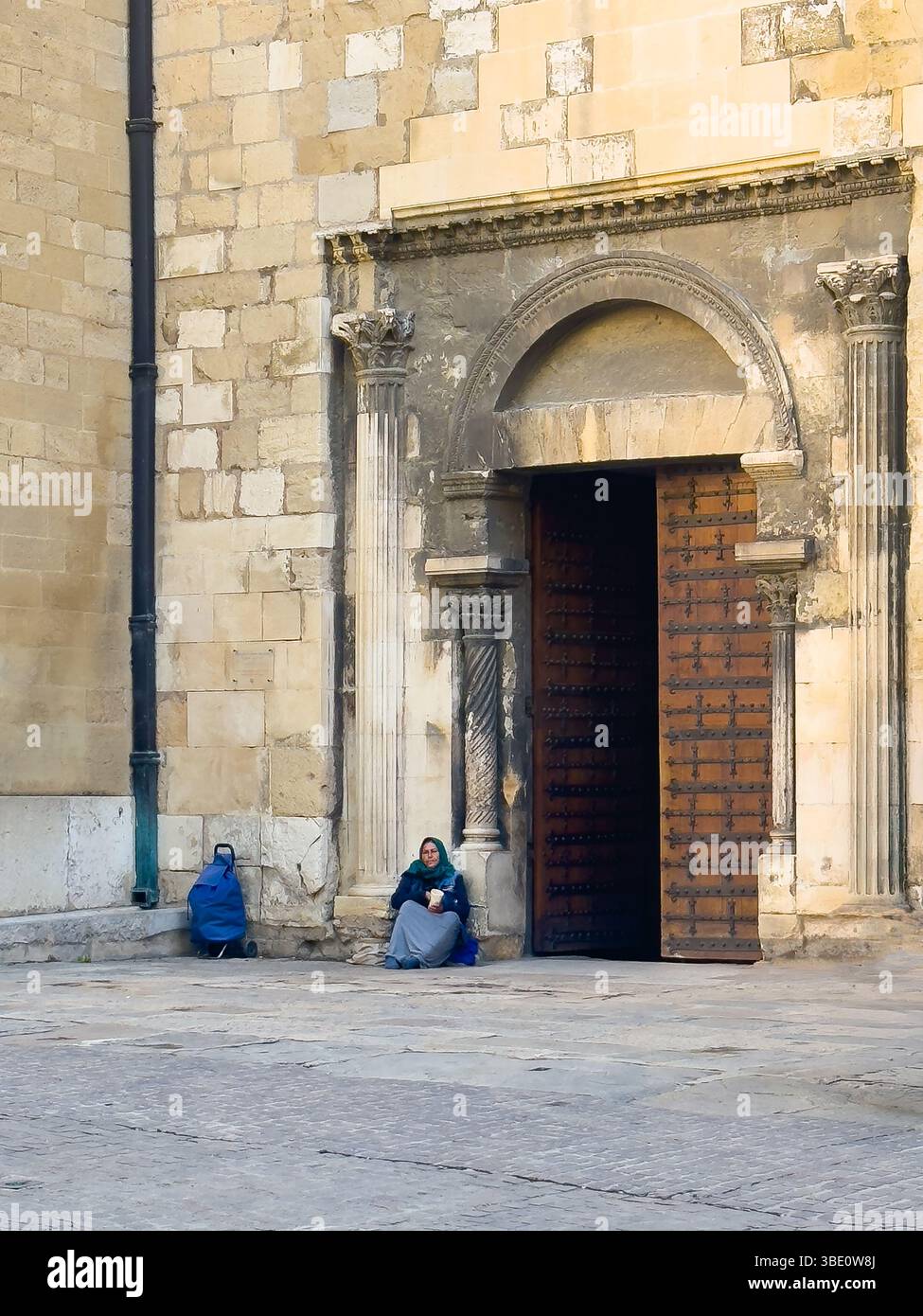 AIX-en-Provence, Francia - 10 luglio 2024: Cattedrale storica di Saint Sauveur, Salvatore. Mendicante femminile di fronte all'ingresso laterale Foto Stock
