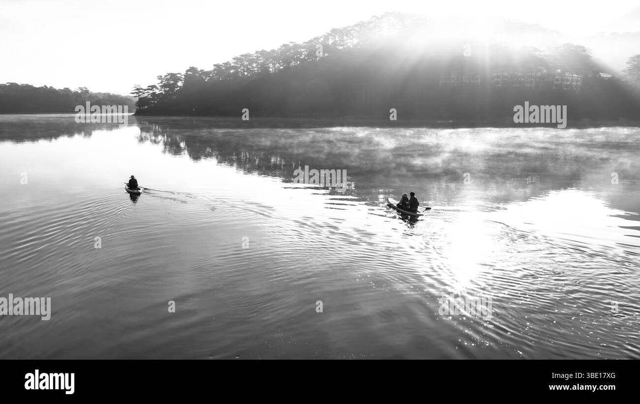 Il mattino sorge nel lago Tuyen Lam di ​​Da Lat, Vietnam. Il sole splende attraverso le colline di pini sulla tranquilla superficie del lago, è meraviglioso Foto Stock