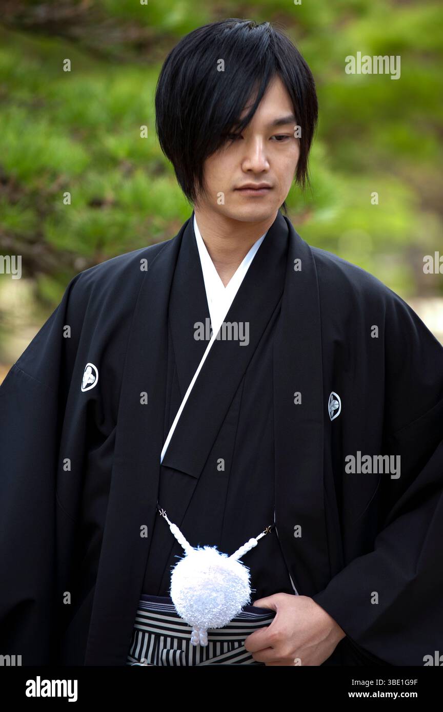 Sposo giapponese "shinro" (新郎) che indossa il tradizionale kimono nero "tomesode" (留袖) con una palla bianca decorativa "haorihimo" con cordoncino in Giappone Foto Stock