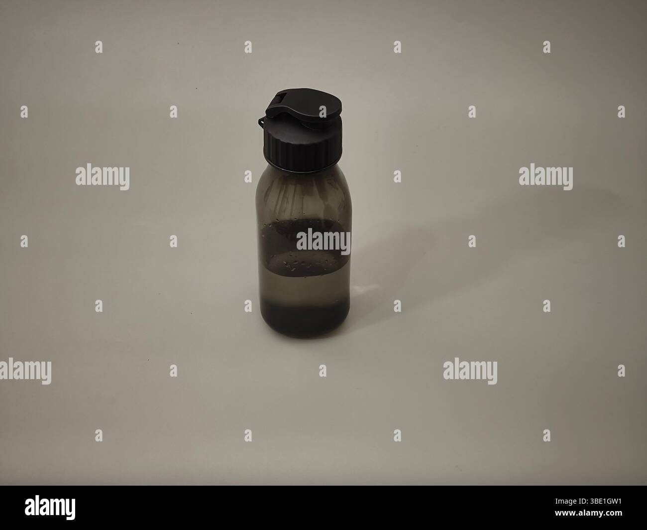 Un bicchierino nero pieno d'acqua su sfondo grigio Foto Stock