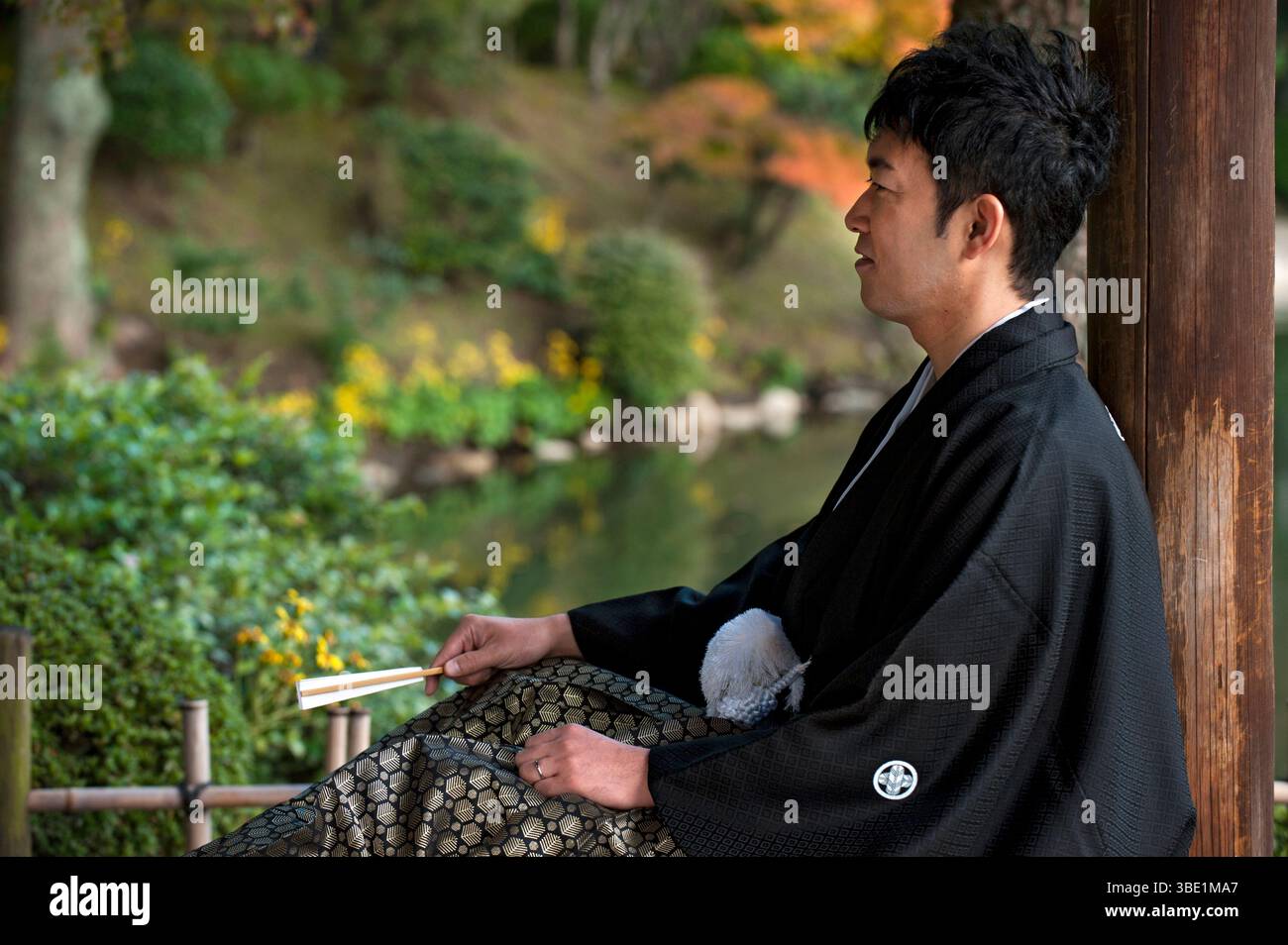 Sposo giapponese "shinro" (新郎) che indossa il tradizionale kimono nero "tomesode" (留袖) con una palla bianca decorativa "haorihimo" con cordoncino in Giappone Foto Stock